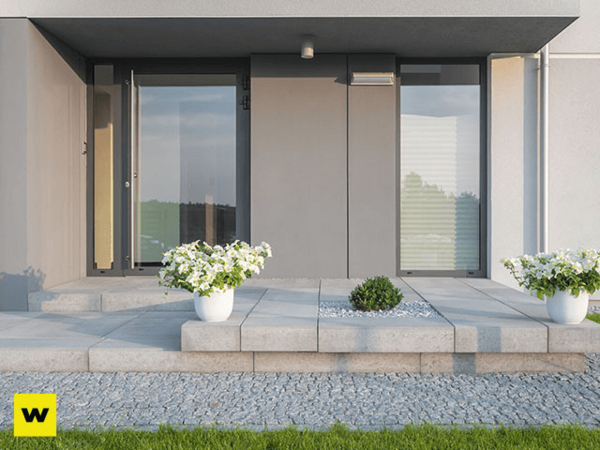 Moderner Hauseingang mit großen Fenstern, Pflanzkübeln und gepflegtem Hauseingangsbereich.